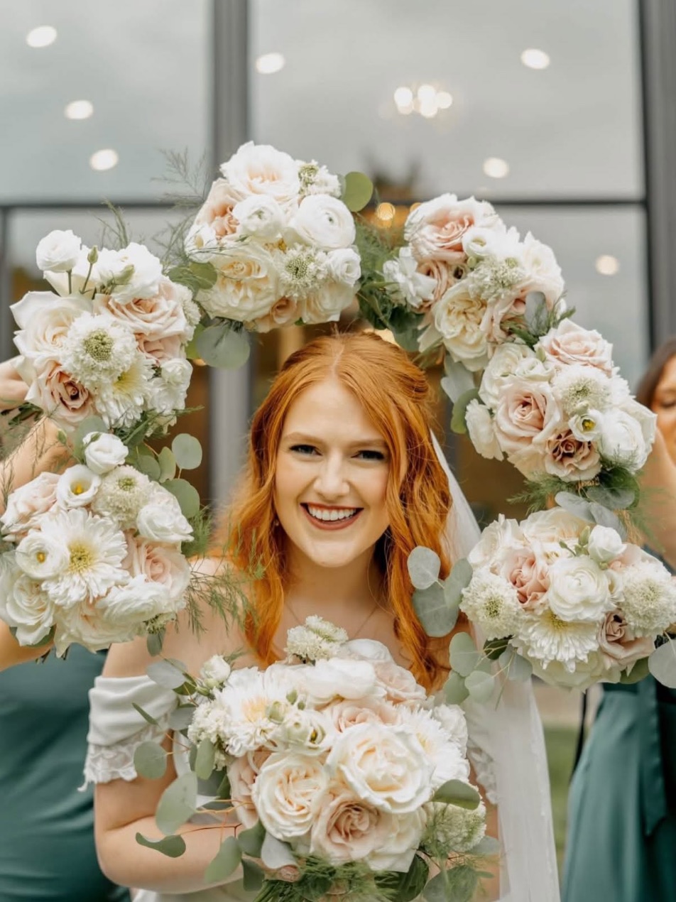A bride framed by her bridesmaids' bouquets