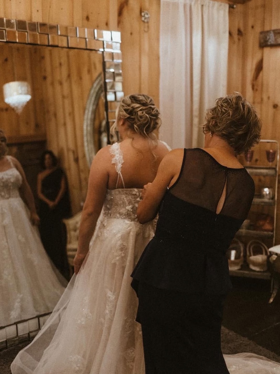 A bride's twisted updo from behind as she is buttoned into her dress